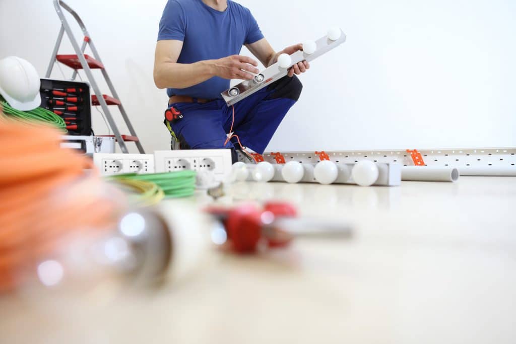 electrician at work with tools, puts the bulbs on a lamp at home, electric circuits, electrical wiring