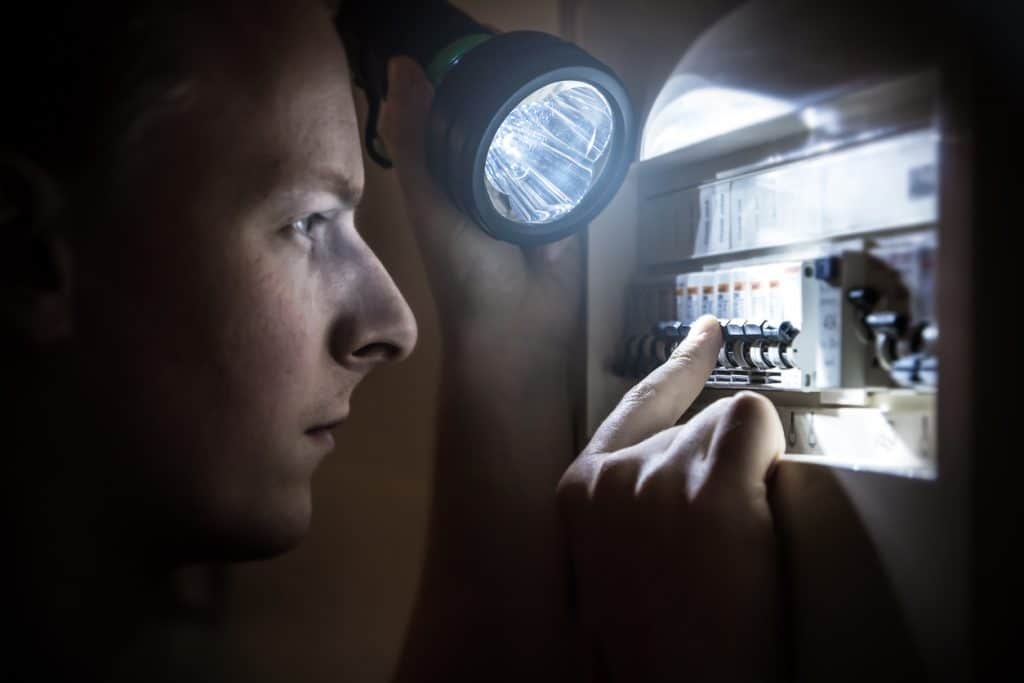 Man restoring power on circuit breaker after electricity outage